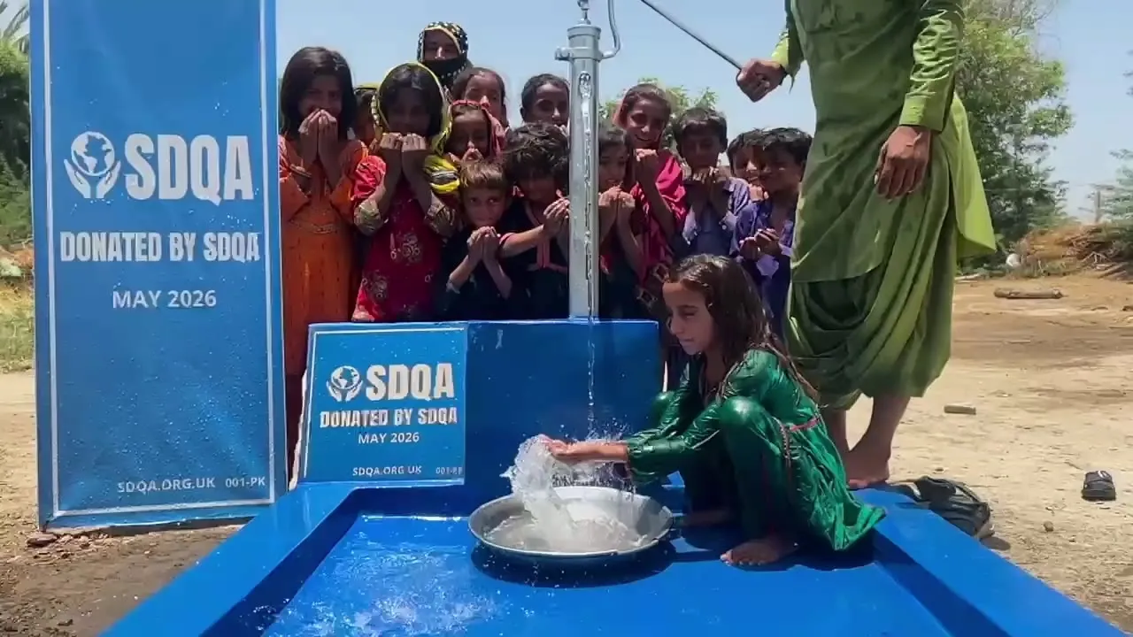 A girl filling a basin at a hand pump